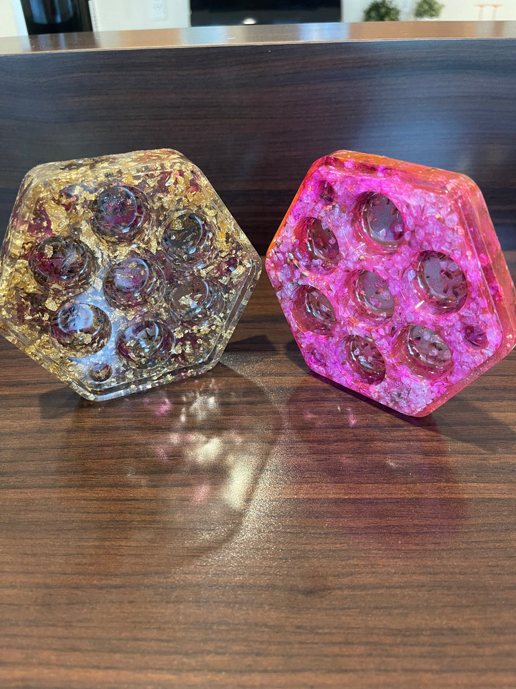 Two hexagon resin dice holders in gold and pink